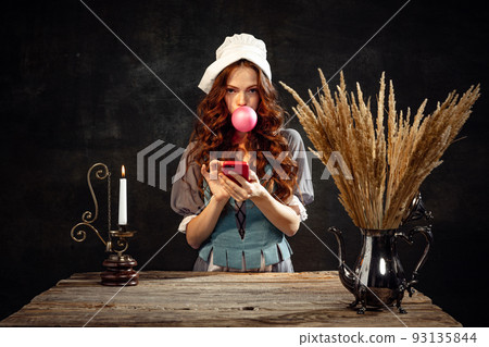 Vintage style. Young charming redhair girl with long curly hair like girl of renaissance eras isolated on dark background. Eras comparison, beauty, art, painting 93135844