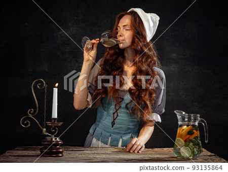 Vintage portrait of young adorable redhead girl in image of medieval person in renaissance style dress isolated on dark background. Comparison of eras Vintage portrait of young adorable redhead girl in image of medieval person in renaissance style dress isolated on dark background. Comparison of eras 93135864