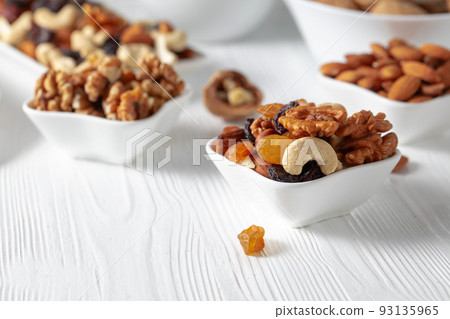 Mix of nuts and raisins on a white wooden table. 93135965