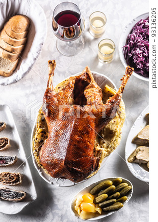Roast goose with side dishes, red cabbage, roast, strudel, potato dumplings, pickles, bread and red wine. Traditional holiday food. Top view. 93136205