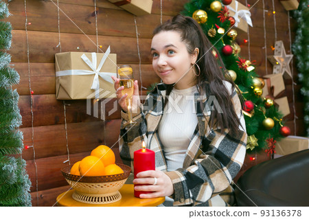 Girl in casual clothes with a glass of champagne near the Christmas tree Girl in casual clothes with a glass of champagne near the Christmas tree 93136378