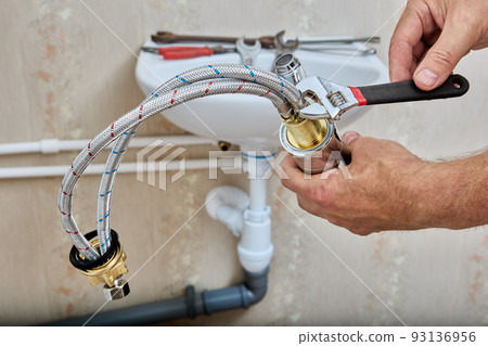 Braided connecting hose for connect water tap to home water supply system, plumber tightens nut with wrench. 93136956