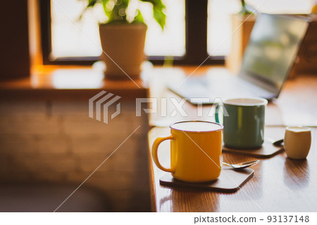 Coffee cups and laptop on the table in cafe. Coffee break. Idyllic place for work. Freelance work place. Morning with coffee and notebook. Cafe interior. Creative space for work. Hot morning drinks. 93137148