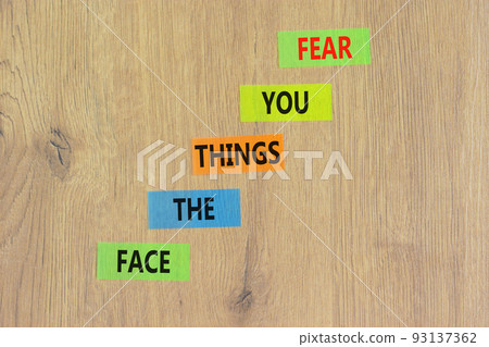 Face the things you fear symbol. Concept words Face the things you fear on color papers on a beautiful wooden background. Business and face the things you fear concept. Copy space. 93137362