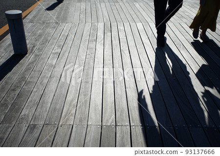 Silhouettes of people reflected on the boardwalk in the evening Silhouettes of people reflected on the boardwalk in the evening 93137666