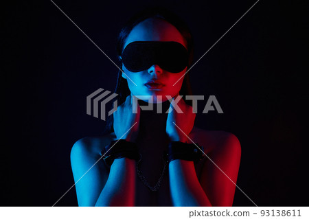 Girl in handcuffs and mask. in color lights. tied hands and