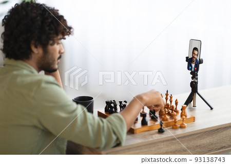 Eastern man playing chess with his friend via video call Eastern man playing chess with his friend via video call 93138743