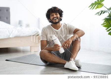 Positive indian guy drinking water while having workout Positive indian guy drinking water while having workout 93138891