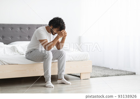 Depressed indian guy sitting on bed at home, copy space 93138926