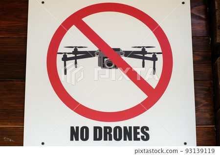 Warning sign of banning use of drones in lake natural reserve. Sign of banning video and photo filming using drones attached on wooden wall closeup 93139119