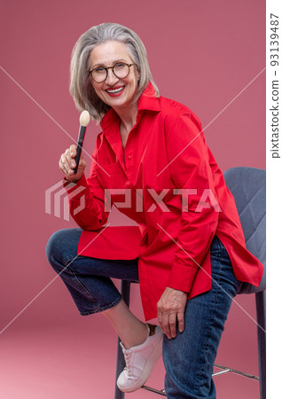 Good-looking mid aged woman in a studio holding a face brush in hand 93139487