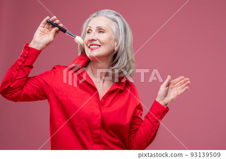 Smiling woman in red with a face brush in hand 93139509