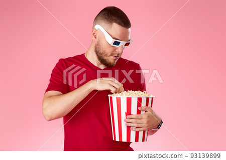 Young caucasian man in 3d glasses eating popcorn Young caucasian man in 3d glasses eating popcorn 93139899