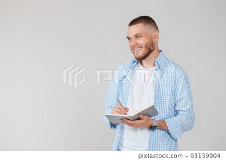 handsome man in blue shirt writing note in notebook handsome man in blue shirt writing note in notebook 93139904