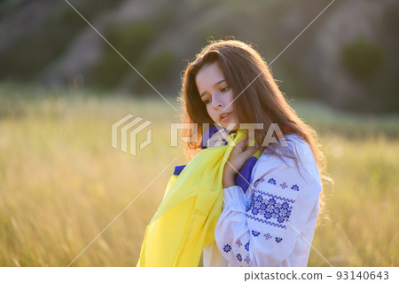 A sad teenage girl holds a Ukrainian flag to her chest. A sad teenage girl holds a Ukrainian flag to her chest. 93140643