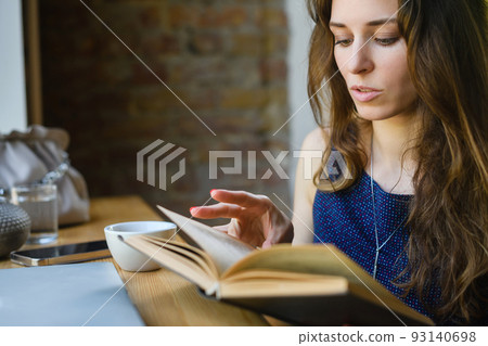 Girl reading a book while having breakfast in a coffee shop 93140698