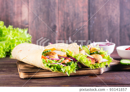 Mexican tortilla wraps with chicken and vegetables on a board on the table Mexican tortilla wraps with chicken and vegetables on a board on the table 93141857