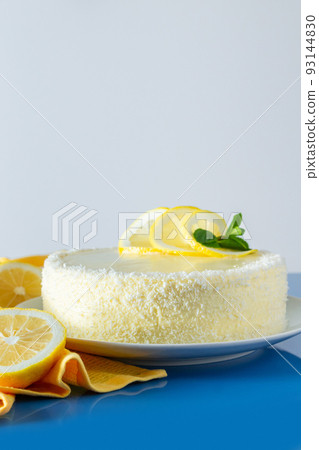 Lemon cake with coconut flakes on blue background. Delicate dessert with cream. Lemon cake with coconut flakes on blue background. Delicate dessert with cream. 93144830