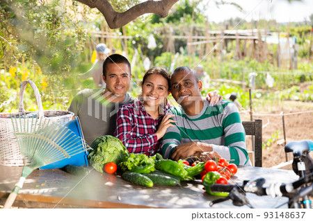 Smiling woman and men farmers sitting at table outdoors Smiling woman and men farmers sitting at table outdoors 93148637