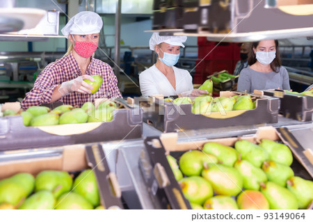 Positive workers in protective masks sort pears 93149064