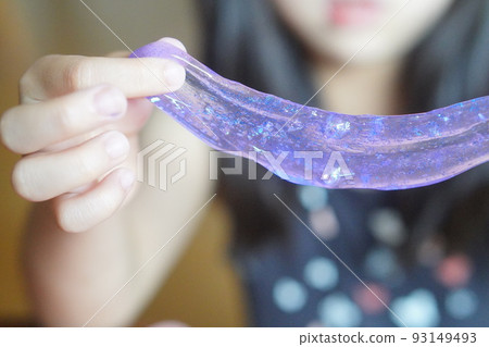 A girl in the second grade (8 years old) playing with handmade slime. I made a cute purple slime. 93149493