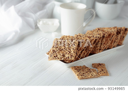 Crackers with sunflower seeds and flax seeds on a white table. Crackers with sunflower seeds and flax seeds on a white table. 93149985