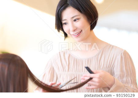 Female hair stylist cutting customer's hair in beauty salon 93150129
