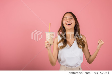 Excited Asian beautiful woman holding drinking brown sugar flavored tapioca pearl bubble milk tea 93152051