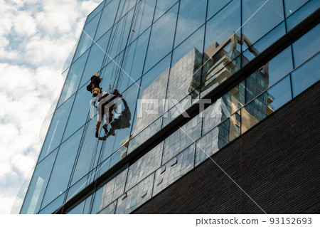Workers cleaning office building windows 93152693