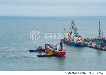 container ship is moored with the help of tugboats to a cargo berth 93154767