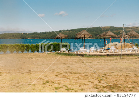 Natural solarium with deck chairs and straw parasols near the river Natural solarium with deck chairs and straw parasols near the river 93154777