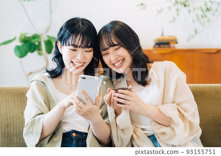 Two smiling women looking at a smartphone 93155751