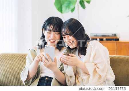 Two smiling women looking at a smartphone Two smiling women looking at a smartphone 93155753
