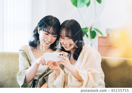 看智能手機的兩個微笑的婦女 93155755
