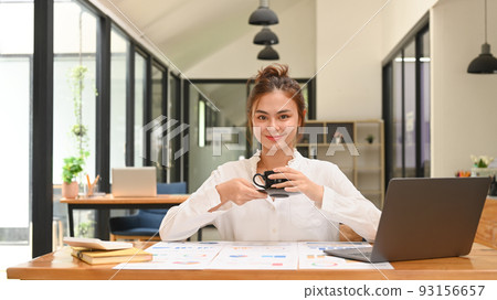 Young businesswoman using laptop and working with financial document at contemporary workplace 93156657