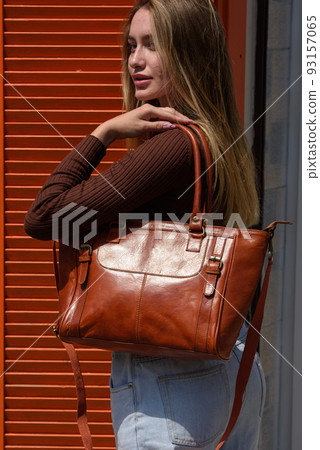 photo of beautiful woman in a blue jeans and brown shirt with orange leather bag photo of beautiful woman in a blue jeans and brown shirt with orange leather bag 93157065