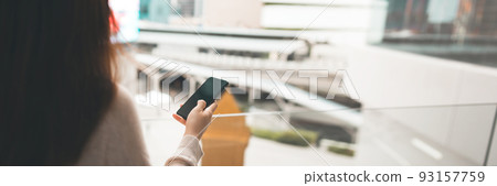 Shoulder view of woman using mobile phone empty screen with blur city banner size background. 93157759