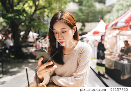 Young adult business asian woman using smartphone listen music at cafe on day. 93157760