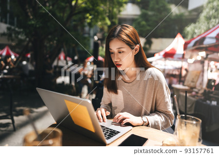 Business freelancer adult asian woman using laptop computer for work at sidewalk cafe 93157761