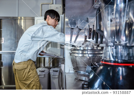 Male staff checking commercial kitchen utensils commercial refrigerator 93158887