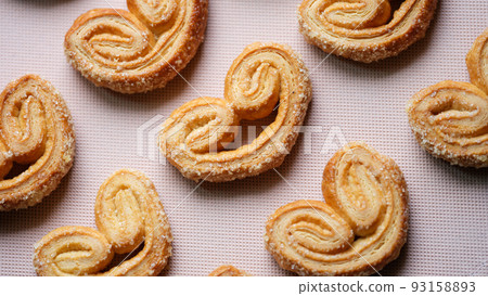Tasty puff pastry cookies with sugar sprinkle on pink background Tasty puff pastry cookies with sugar sprinkle on pink background 93158893