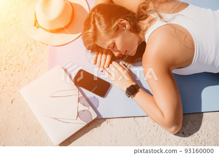 Digital nomad, woman in the hat, a business woman with a laptop sits on the rocks by the sea during sunset, makes a business transaction online from a distance. Freelance, remote work on vacation. 93160000