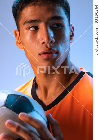 Close-up portrait of young man, professional football player posing isolated over blue studio background in neon light Close-up portrait of young man, professional football player posing isolated over blue studio background in neon light 93160264