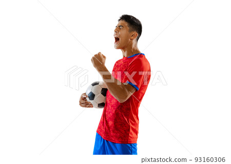 Portrait of young emotive man, motivated football player in uniform with ball posing isolated over white studio background. Winning game 93160306
