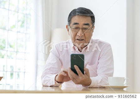 A smiling man in his late 70s with a smartphone A smiling man in his late 70s with a smartphone 93160562