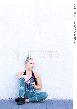 Sport and lifestyle concept, sporty blonde woman resting after doing sports outdoors. Attractive 93161044