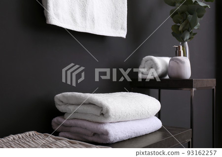 Clean soft towels on stand near black wall Clean soft towels on stand near black wall 93162257