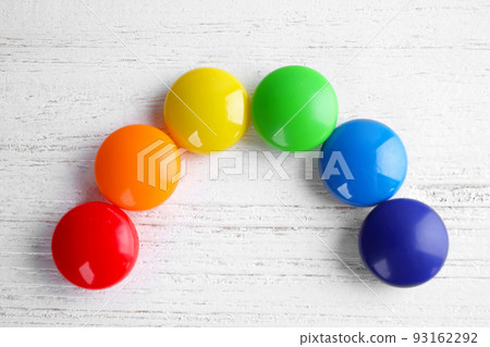 Bright magnets on white wooden background, flat lay. Rainbow colors Bright magnets on white wooden background, flat lay. Rainbow colors 93162292