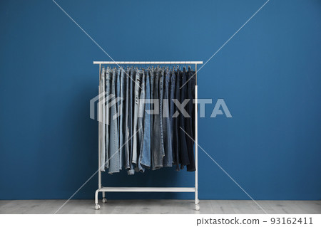 Rack with stylish jeans near blue wall Rack with stylish jeans near blue wall 93162411