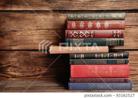 Collection of different books on table against wooden background Collection of different books on table against wooden background 93162527